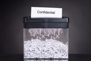 Shredded destroying confidential document over black background