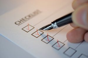 Checklist concept - checklist box with red checkmark, paper and a pen with checklist word on table