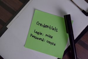 Credentials, Login and Password write on sticky notes isolated on Wooden Table.