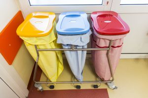 Three recycle bins in a hospital for different kinds of waste.