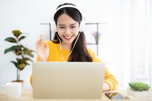 Young asian woman in headphone having conversation chatting while using laptop at house. Work at home, Video conference, Online meeting video call, Virtual meetings, Remote learning and E-learning